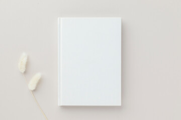 White book blank cover mockup on a beige background with dry flower, flat lay, mockup
