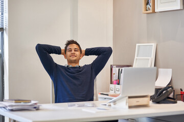Success is earned not given. Portrait of a content businessman sitting at her desk in an office.