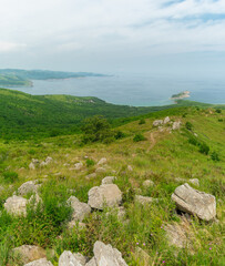 Fototapeta na wymiar Summer landscape. Large boulders on top of green hills against the backdrop of the sea