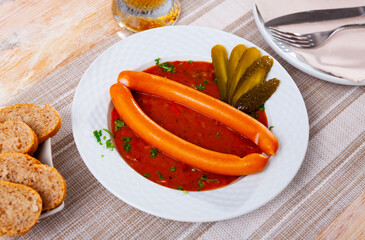 Appetizing Vienna sausages with goulash sauce on a served table