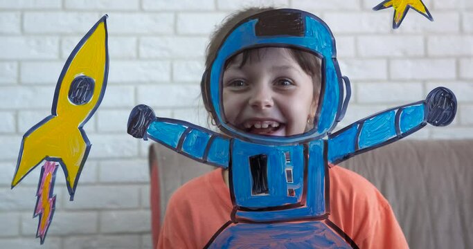 Play Nasa at home. A happy spacechild want to be an astronaut from home by the glass picture of cosmos at home.