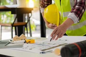 Young engineers and architects design, plan, measure the layout of blueprints with tabletop tools...