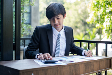 Young Asian businessman financial market analyst sits at their desks and calculate financial graphs showing the results of their investments planning the process of successful business growth