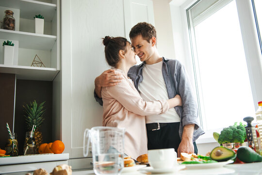 Couple hugging while standing in the kitchen wanting to make breakfast. Cooking, together, kitchen, relationship. Healthy food. Activity relationship - Powered by Adobe
