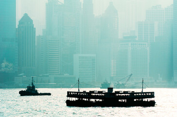 South over Hong Kong Harbour, China. Star Ferry passenger boat and tug silhouetted against Hong...