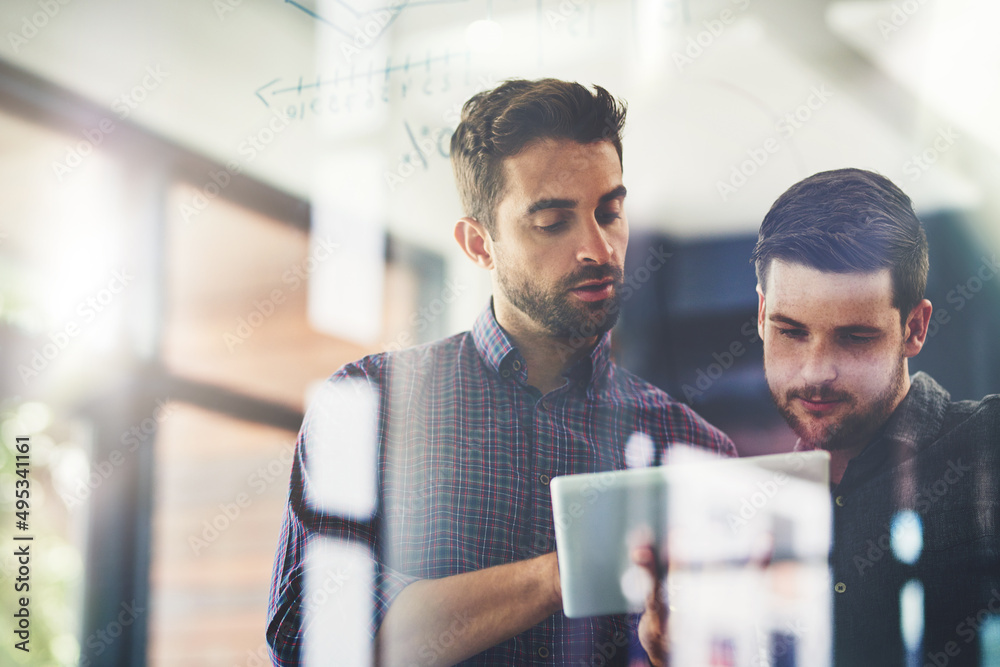 Poster working on their top ideas to expand their company. shot of two young businessmen using a digital ta