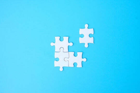 Group of white puzzle jigsaw pieces on blue background. Concept of solutions, mission, success, goals, cooperation, partnership, strategy and puzzle day