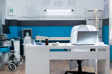 Inside of empty contemporary doctor office equipped with professional medical equipment used for clinical examination. Hospital room with nobody in it having pills bottle on table. Health are services