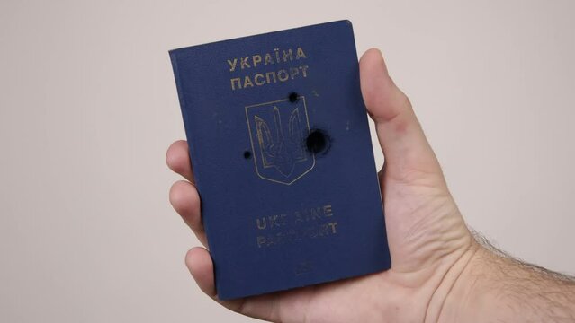 War between Russia and Ukraine. The concept of murder, occupation, aggression. Male hand holds a blue passport of Ukraine.