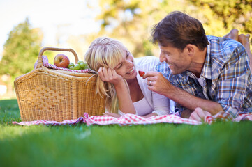 Open up. Shot of an affectionate couple enjoying a picnic in the sun.