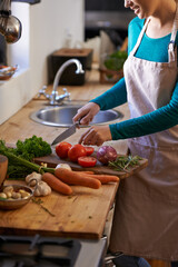 Shes a natural at this. Cropped shot of an attractive young woman chopping vegetables in the kitchen.