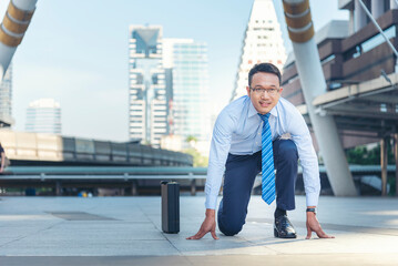 Businessman start kneeling city street race business goal winner challenge. Asian man look at camera smile face wear glasses. Man happiness time start up a business goal. Businessman race concept