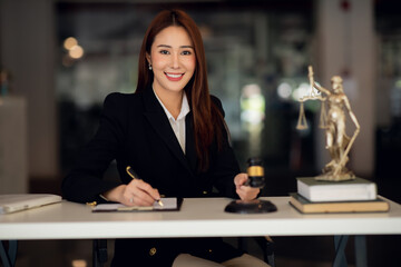 Attractive young lawyer in office Business woman and lawyers discussing contract papers with brass scale on wooden desk in office. Law, legal services, advice, Justice and real estate concept.