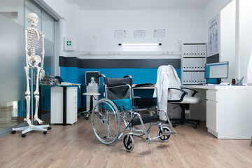 Medical wheelchair standing in empty doctor office with nobody in it ready for patient examination. Hospital office equipped with professional instrument. Health care services support