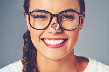 Fototapeta na wymiar Happiness blooms from within. Studio shot of a young woman with a flower on the tip of her nose.