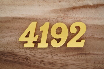 Golden Arabic numerals on a real brown and white wooden floor number 4192