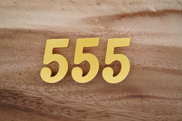 Golden Arabic numerals on a real brown and white wooden floor number 555