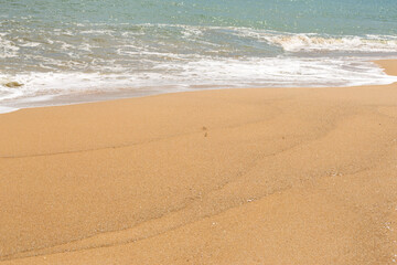 Fototapeta na wymiar Blue sea waves with foam on yellow sand beach.