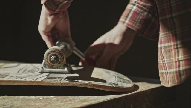 Close-up skateboard, Male person doing maintenance on a skateboard in his workshop with Allen key or Hex key tool. Maintenance of professional skateboarding