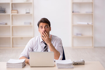 Young male employee unhappy with excessive work in the office