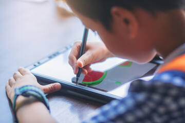 Boy with digital pencil drawing and painting on a tablet at home to develop the skills of children...