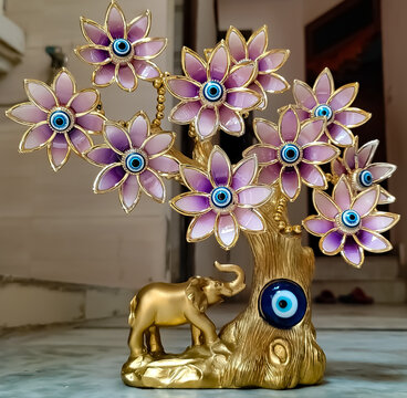 A vastu Blue devil eye along with an elephant and 10 vastu devil eye flowers in gold colour on fang sui item in bright light