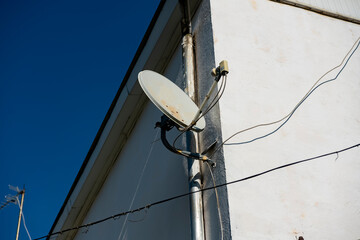 Satellite dish on the corner of a residential building.