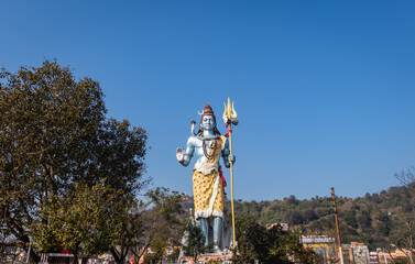 Naklejka premium hindu god shiva statue with bright blue sky background at morning from different angle