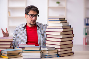 Young male student and too many books in the classroom