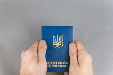 A mature man holds a Ukrainian passport in his hand. ID card against a gray background