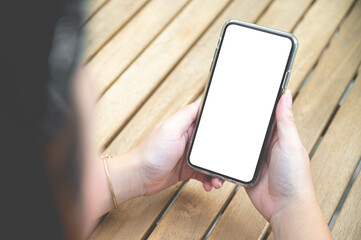 Close up women using a smartphone with an empty white screen at the wooden interior cafe.