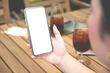 Close up women using a smartphone with an empty white screen at the wooden interior cafe.