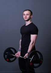 Fototapeta na wymiar Guy with a barbell in a black fitness T-shirt muscular bodybuilder heavy fit, from exercise active for gym for healthy athletic, background deadlift. Man young motivation, practicing arm