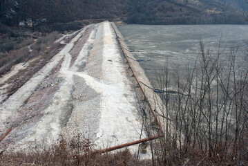 Barrier stopping the flow of copper and gold mining mining residuals into a settling basin,...