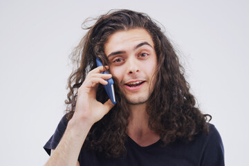 So what have you been up to. Studio shot of a young man using a mobile phone against a grey background.