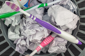 Toothbrushes and toothpaste in the trash. Garbage in a bucket.