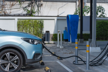 Electric car parked to charge battery from station power supply, vehicle charging technology.
