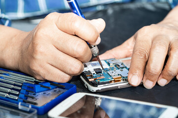 Technician repairing inside of mobile phone by soldering iron. Integrated Circuit. the concept of...