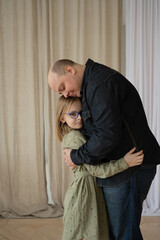 Dad and daughter spend a good time, hugging. Portrait of a family in the interior. Father's Day.