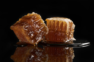 Organic honeycomb with dripping honey on black background