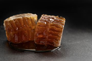 Organic honeycomb with dripping honey on black slate