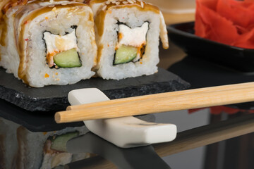 rolls with cream cheese and cucumber close-up next to bamboo sticks