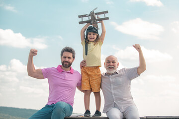 Three generations of men together, portrait of smiling son, father and grandfather with a toy airplane. Child boy playing with plane. Family adventure, imagination, innovation and inspiration.