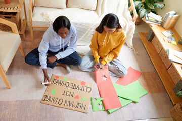 College students making placard for upcoming global climate change protest on the floor in dormitory room