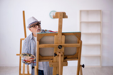 Fototapeta na wymiar Old man enjoying painting at home