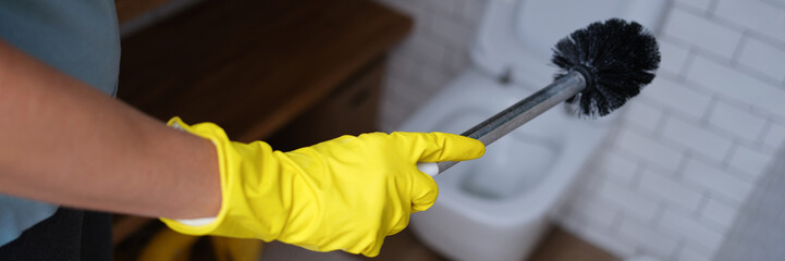 Hand in a glove holds a toilet brush, close-up
