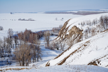 Winter landscape, mountains covered with snow, Russia Southern Urals Bashkortostan, valley of the Karlamanskaya cave. Winter forest, view from the mountain to the fields, morning, ravine