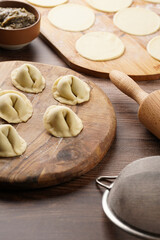 Process of preparation of traditional ukrainian east european dish varenyky - dumplings stuffed with potato-mushroom paste. Wooden background
