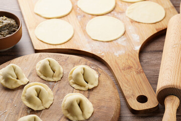 Process of preparation of traditional ukrainian east european dish varenyky - dumplings stuffed with potato-mushroom paste. Wooden background