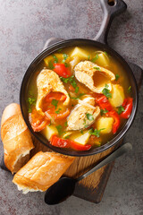 Caldeirada de peixe Portuguese fish stew with potatoes, peppers, tomatoes and onions close-up in a bowl on the table. Vertical top view from above
